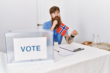 Caucasian man with long beard at political campaign election holding norwegian flag serious face...