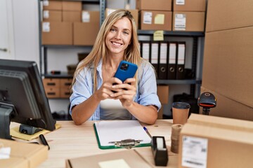 Young blonde woman ecommerce business worker using smartphone at office