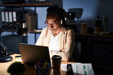 Beautiful black woman working at the office at night skeptic and nervous, disapproving expression...