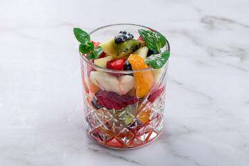 glass with pieces of different fruits and berries