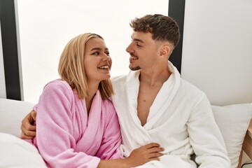 Young caucasian couple smiling happy and hugging on the bed at home.