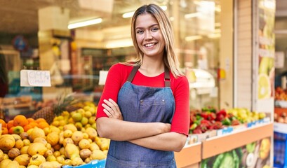 Young hispanic woman shop assistant standing with arms crossed gesture at fruit market