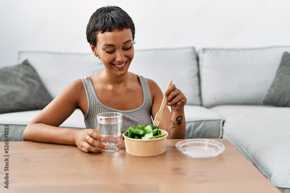 Sticker Young hispanic woman smiling confident eating salad at home