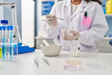 Young latin woman wearing scientist uniform working at laboratory