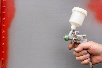A spray gun for painting works in the hand of a master