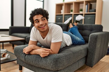 Young hispanic man smiling happy lying on the sofa at home.