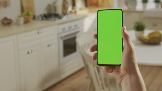Handheld Camera: Point of View of Man at Kitchen Room Using Phone With Green Mock-up Screen Chroma Key Without Track Points Surfing Internet Watching Content Videos Blogs. Swipe Up and Tap Center