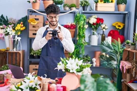 Young hispanic man florist make photo to flowers at florist shop