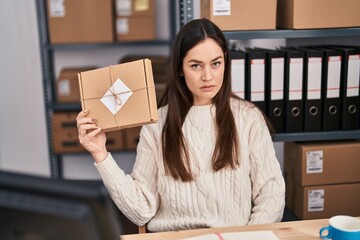 Young brunette woman working at small business ecommerce thinking attitude and sober expression...