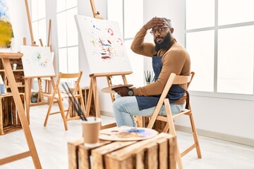 African american artist man painting on canvas at art studio stressed and frustrated with hand on head, surprised and angry face