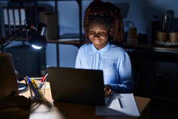 African woman working at the office at night with a happy and cool smile on face. lucky person.