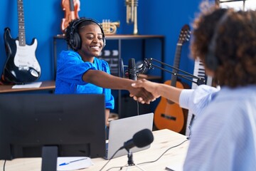 African american women musicians smiling confident shake hands at music studio