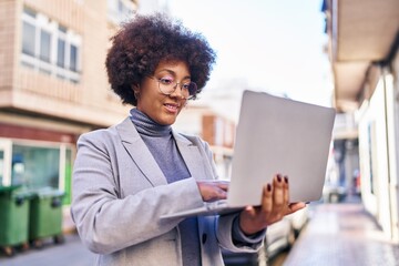 African american woman executive smiling confident using laptop at street