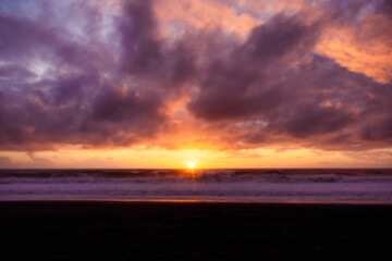 Obraz premium Paisaje de atardecer en la playa con ocaso en el mar y nubes iluminadas por el sol