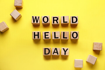 Wooden cubes with text WORLD HELLO DAY on yellow background
