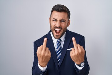 Handsome hispanic man wearing suit and tie showing middle finger doing fuck you bad expression,...