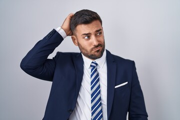 Handsome hispanic man wearing suit and tie confuse and wondering about question. uncertain with...