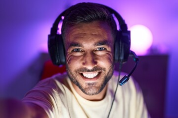 Young hispanic man streamer smiling confident make selfie by camera at gaming room