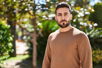 Young hispanic man with relaxed expression standing at park