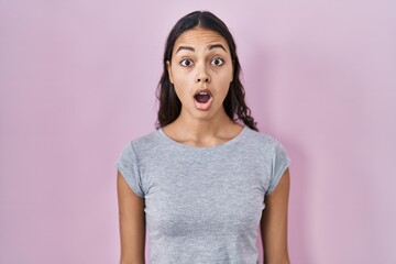 Young brazilian woman wearing casual t shirt over pink background afraid and shocked with surprise expression, fear and excited face.