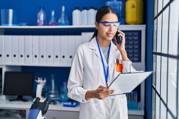 Young african american woman scientist talking on the smartphone at laboratory