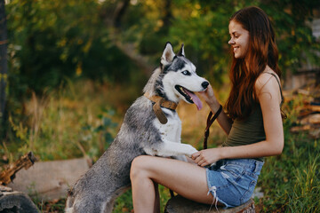 Young woman with red hair plays and smiles with her husky dog ​​on a leash while hiking in the forest in autumn © SHOTPRIME STUDIO