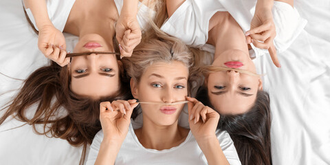 Funny young women lying on bed, top view