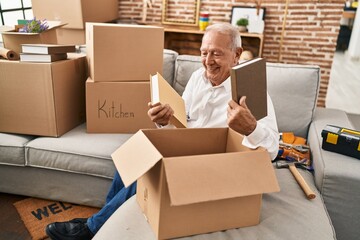 Senior man smiling confident unboxing package at new home