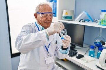 Senior man wearing scientist uniform mixing liquid at laboratory