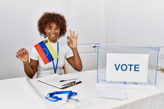 Young african american woman at political campaign election holding venezuela flag doing ok sign with fingers, smiling friendly gesturing excellent symbol