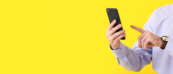 Businessman using mobile phone on yellow background with space for text