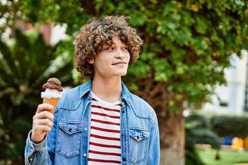 Young hispanic man eating ice cream cone at the park