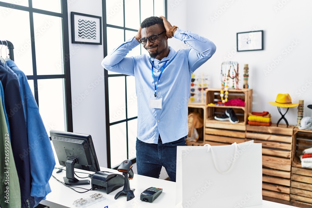 Wall mural Young african man working as manager at retail boutique doing bunny ears gesture with hands palms looking cynical and skeptical. easter rabbit concept.