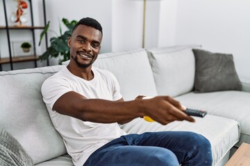 Young african american man watching tv drinking coffee at home