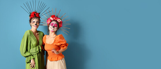 Women with painted skull on faces against blue background with space for text. Halloween celebration