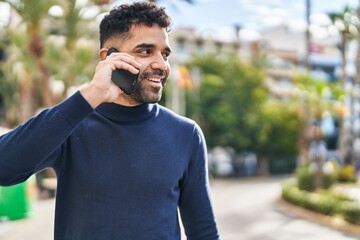 Young hispanic man smiling confident talking on the smartphone at park