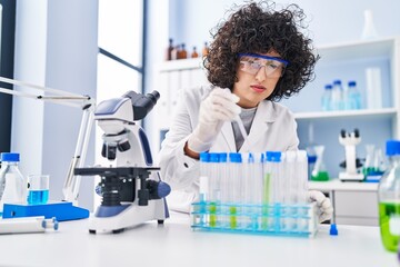 Young middle east woman scientist pouring liquid on test tubes at laboratory