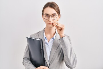Young caucasian woman wearing business clothes and glasses mouth and lips shut as zip with fingers....