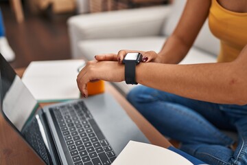 Young chinese woman using smartwatch sitting on sofa at home