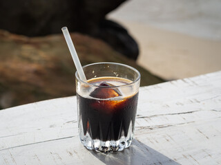 Top view of a glass with iced coffee on a white wooden table