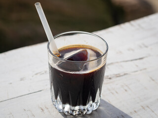 Top view of a glass with iced coffee on a white wooden table