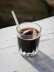 Top view of a glass with iced coffee on a white wooden table