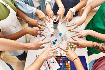 Group of people doing victory sign with fingers together at art studio.