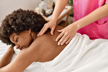 Obraz na płótnie Canvas Young african american woman having back massage at beauty center