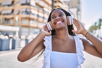 Young african american girl smiling happy listening to music at the promenade.