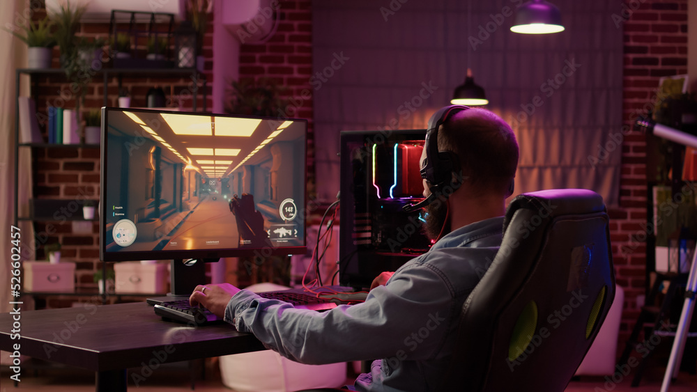 Fototapete man using pc gaming setup relaxing playing multiplayer online action game talking to team on headset