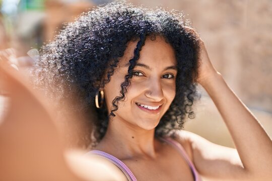 Young hispanic woman smiling confident making selfie by the camera at street