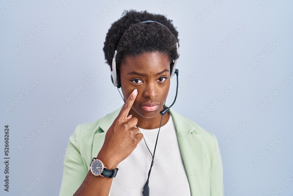 Wall mural African american woman wearing call center agent headset pointing to the eye watching you gesture, suspicious expression