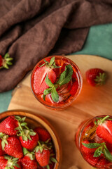 Board with glasses of strawberry lemonade on green background, top view