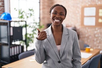 African american woman at the office smiling happy and positive, thumb up doing excellent and approval sign